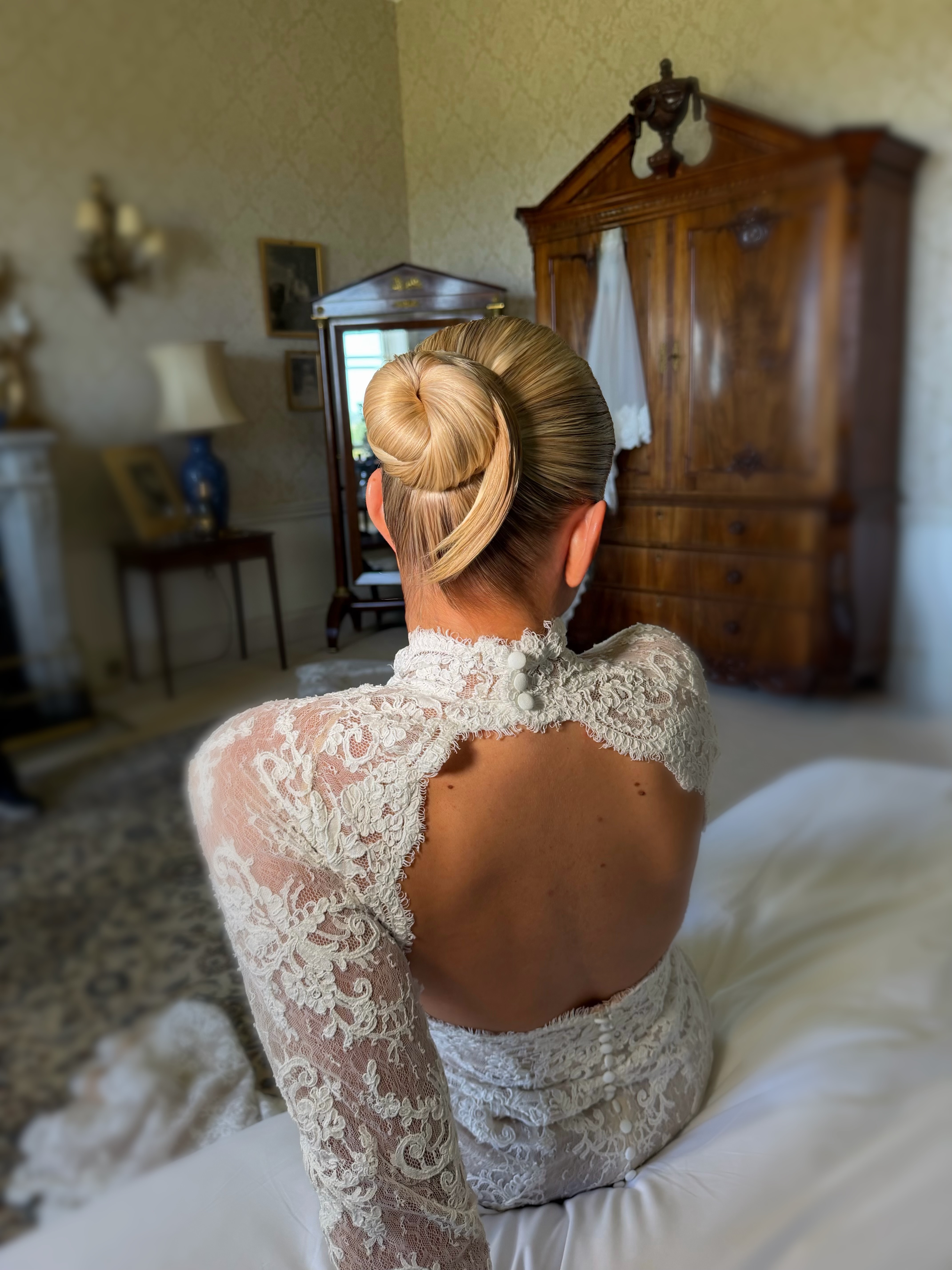 Bride with sleek chignon bun, open-back lace gown