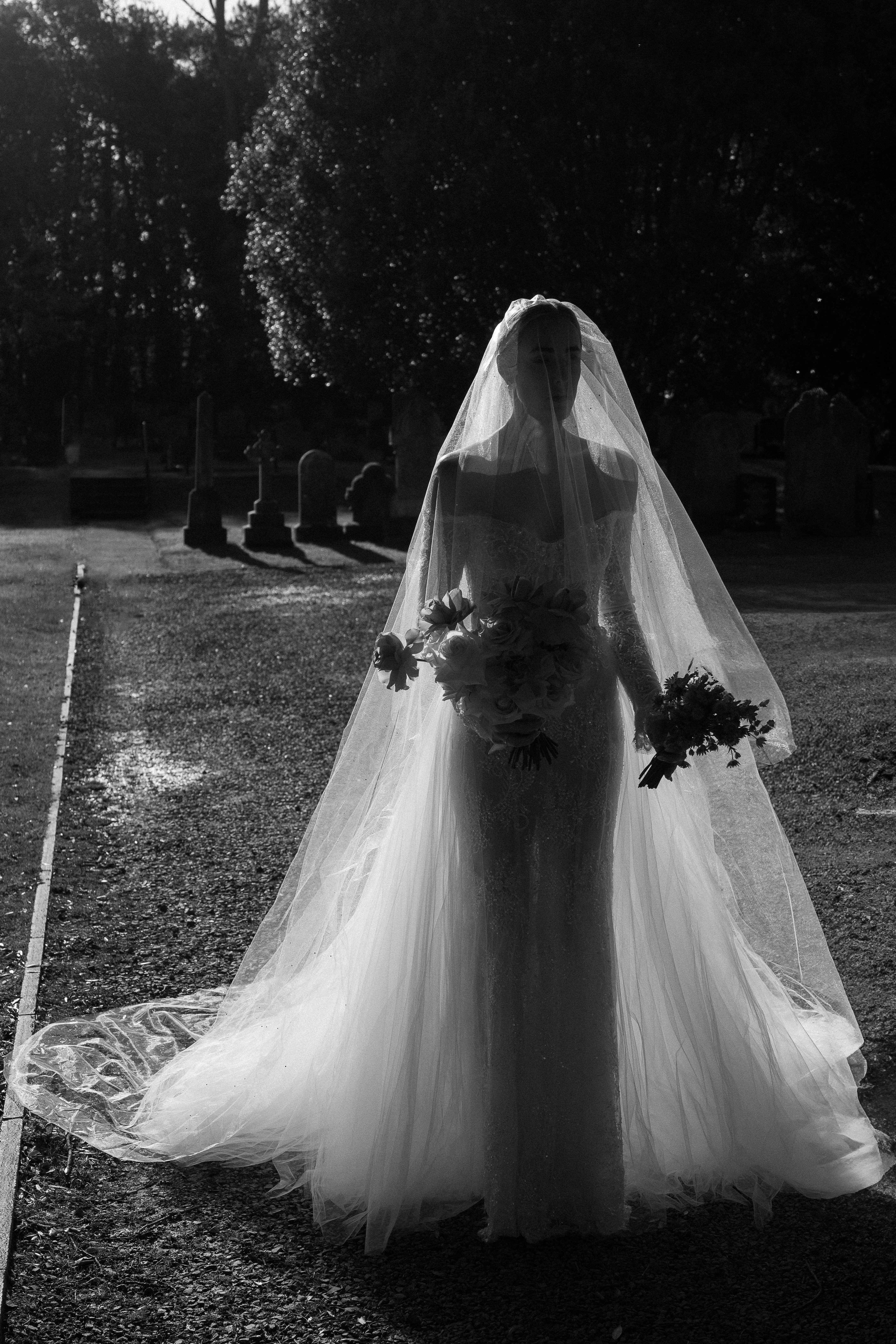 Bride with long veil in churchyard